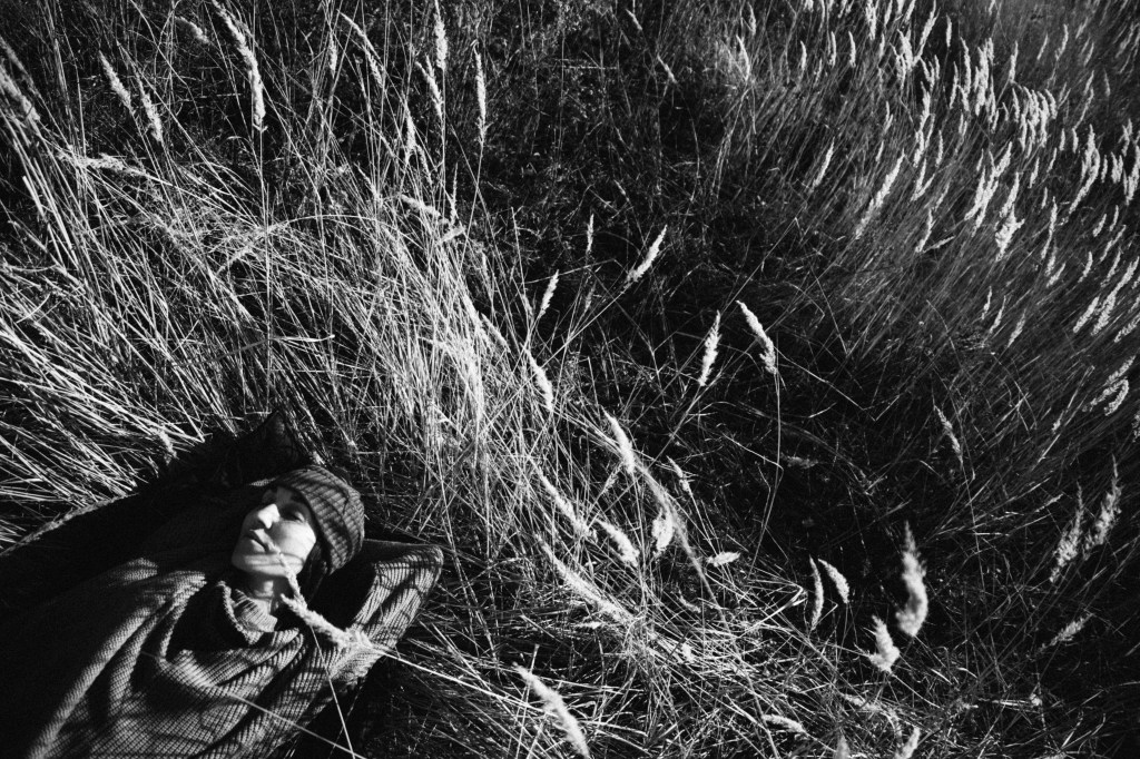 Girl lying in a grassy autumn field. Black and white photography.