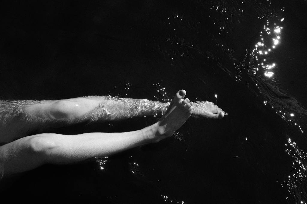 Woman's slim legs in dark and sunlit water.